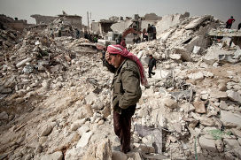 Житель Алеппо стоит среди развалин своего дома